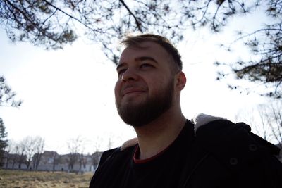 Portrait of young man looking away against sky