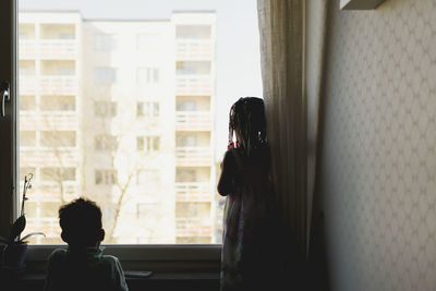 Girl looking through window