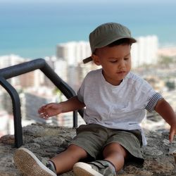 Boy sitting against cityscape