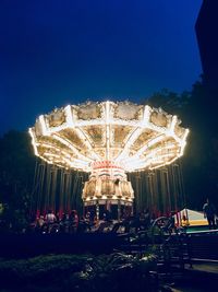 Illuminated ferris wheel against clear sky at night