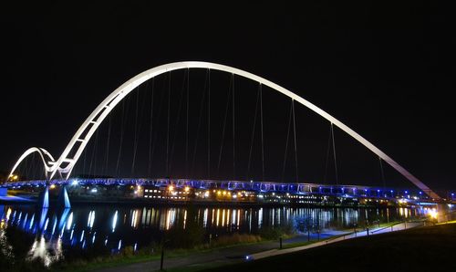 Illuminated ferris wheel against sky in city at night