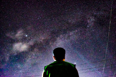 Rear view of silhouette man against sky at night