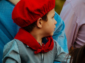 Close-up of boy wearing red hat looking away while sitting with parents