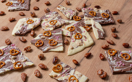 White and brown chocolate prepared for a broken chocolate topped with pretzel, sugar pearls and nuts