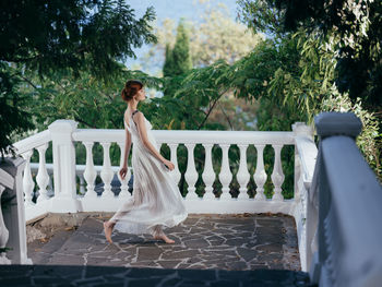 Woman standing by railing against trees