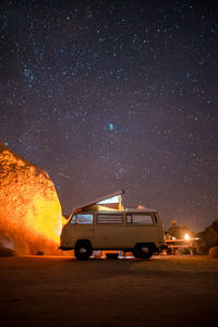 Van on field against star field in sky at night