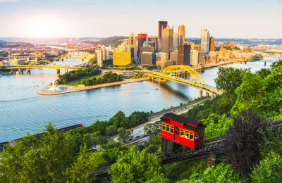 View of city by river and buildings against sky