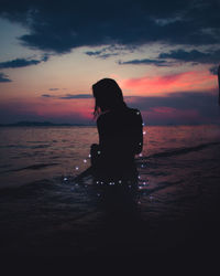 Silhouette woman looking at sea against sky during sunset