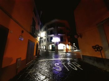 Illuminated street amidst buildings at night