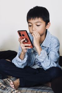 Young man using mobile phone while sitting on sofa at home