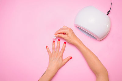 Cropped hands of woman holding telephone against white background