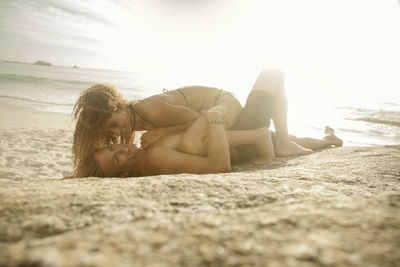 Woman lying down on beach against sky