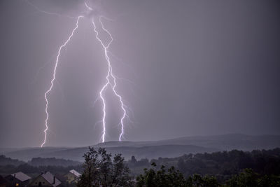 Lightning over mountains against sky at night