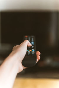 Cropped hand using television set remote control at home