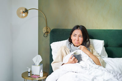 Young woman sitting on bed at home