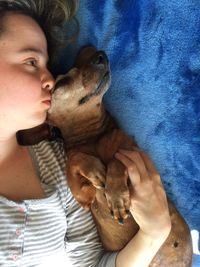 Directly above shot of woman with dog lying on bed