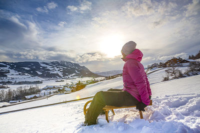 Woman on snowcapped mountains against sky during winter