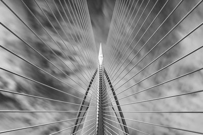 Low angle view of bridge cables against clouds