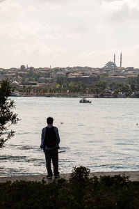 Rear view of man looking at river against sky