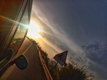 Tilt image of car against sky during sunset