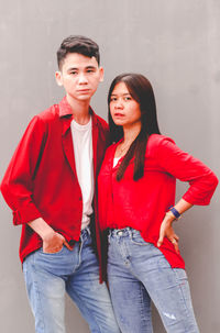 Portrait of smiling young woman standing against wall