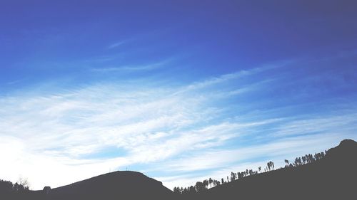 Low angle view of silhouette mountain against blue sky