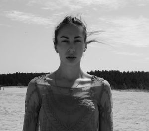 Portrait of beautiful woman standing on land against sky