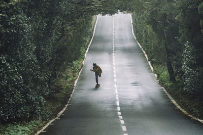 Man skateboarding on road amidst forest at garajonay national park
