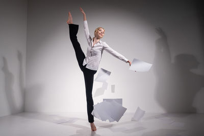 Midsection of woman with arms raised against wall