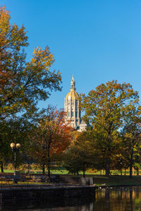 Trees by building against sky during autumn