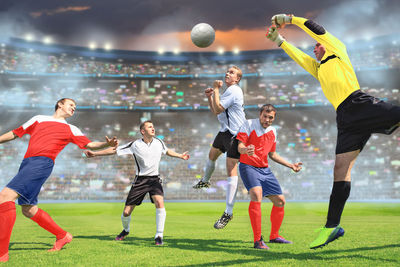 Players playing soccer on field in stadium