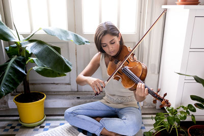 Young woman sitting on a potted plant