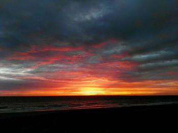 Scenic view of sea against dramatic sky during sunset