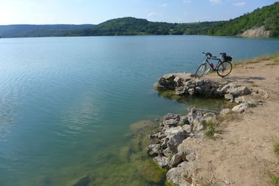 Bicycle by lake against sky