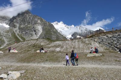 Rear view of people walking on mountain against sky