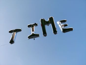 Helium ballons spell out time against blue sky