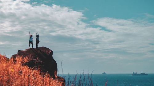 People standing on sea shore against sky