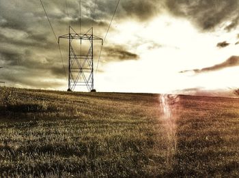 Electricity pylon on field against sky