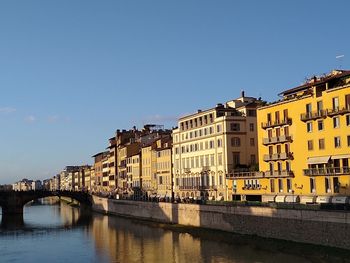 Bridge over river by buildings against sky in city