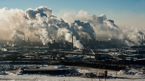 Smoke emitting from factory against sky