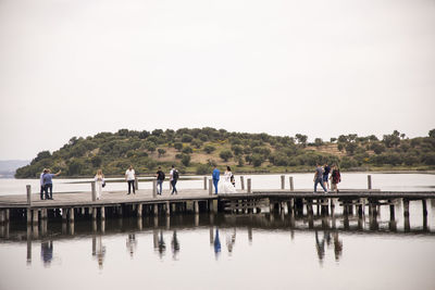 People on lake against clear sky