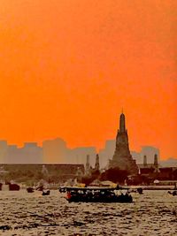 Boats in sea against orange sky during sunset