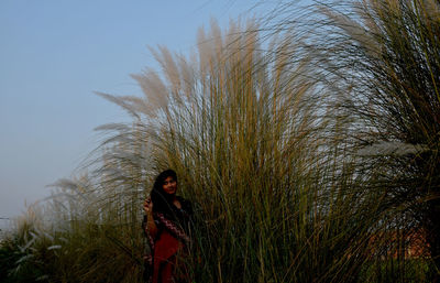 Woman standing by plants against sky