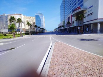 Road by buildings against sky in city