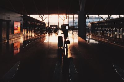 Silhouette woman with luggage walking on floor at airport