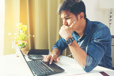 Man using mobile phone while sitting on table