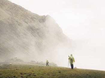 Rear view of men standing on mountain against sky