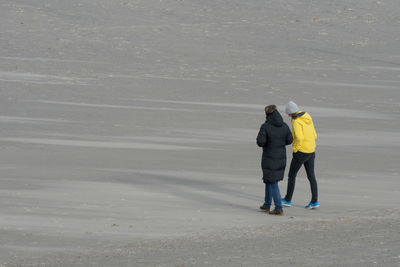 Rear view of couple walking on beach