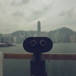 Close-up of coin-operated binoculars against cityscape