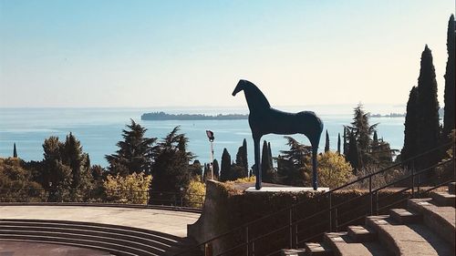 Statue of birds by sea against clear sky